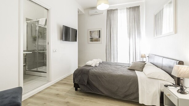 Ein modernes Schlafzimmer mit Bett, Nachttisch und einer Duschkabine aus Glas.
