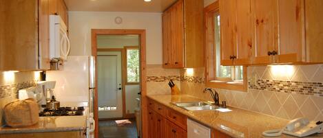 A kitchen with wooden cabinets, a countertop, a sink, a stove, and a dishwasher.