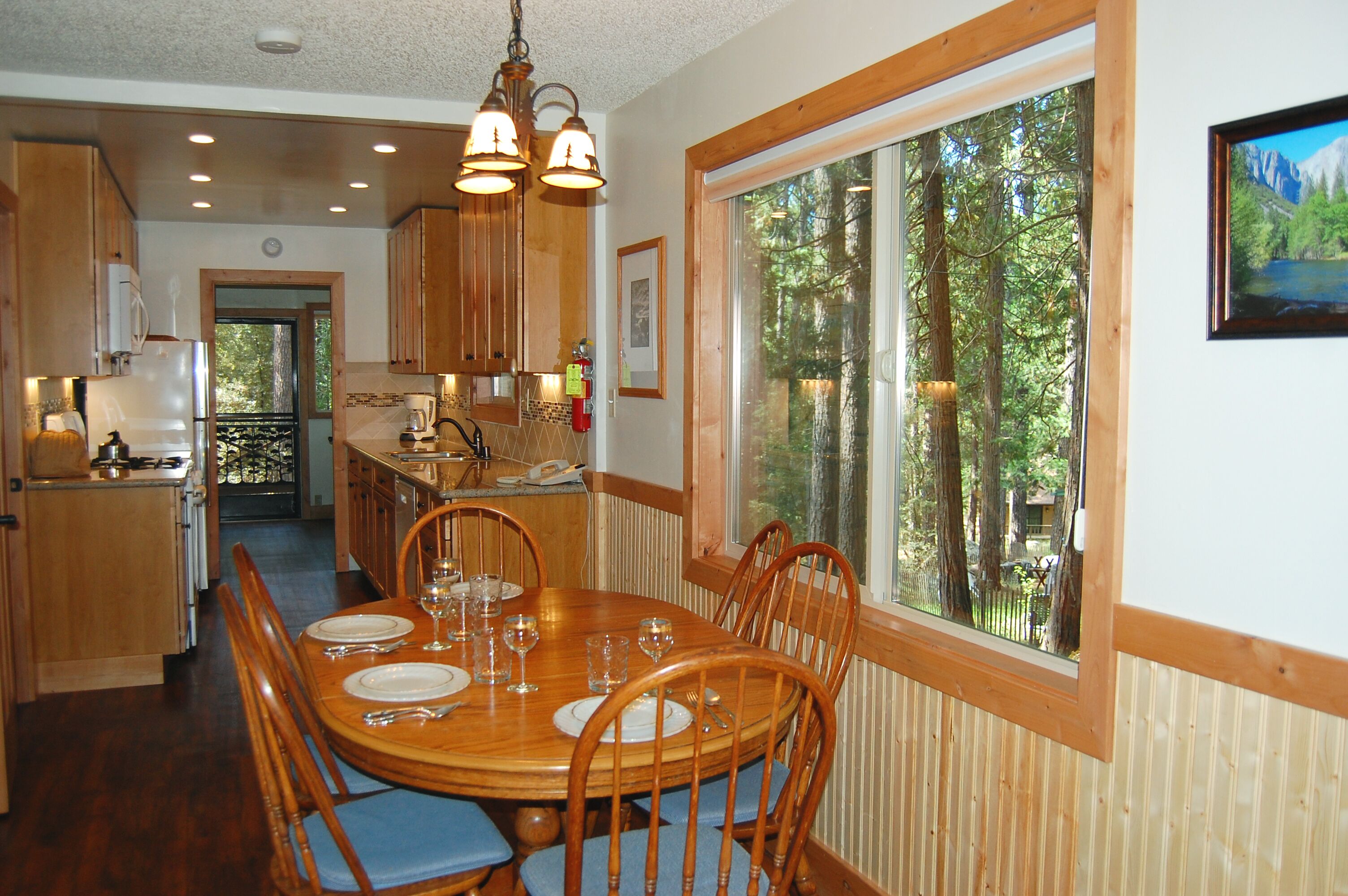 A wooden dining table set with plates, glasses, and cutlery, surrounded by chairs.