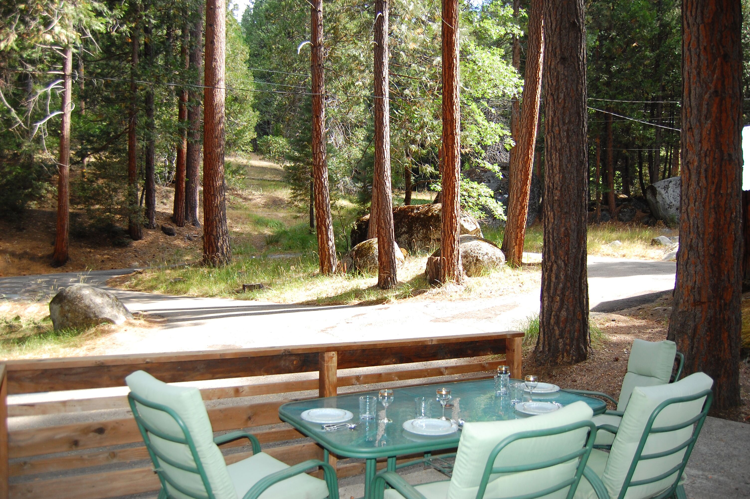 Een eettafel met stoelen buiten, omgeven door bomen.