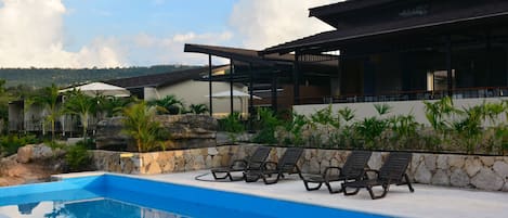 Una piscina al aire libre, sillones reclinables de piscina