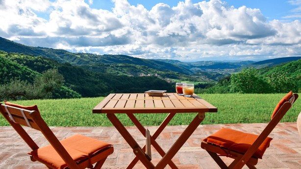 A wooden table and two orange chairs on a patio with a scenic view of green hills and a clear sky. - Ancient Plan. Appart in the Greenest Umbria: Nature, History, Genuineness, Relax (Nocera Umbra (PG))