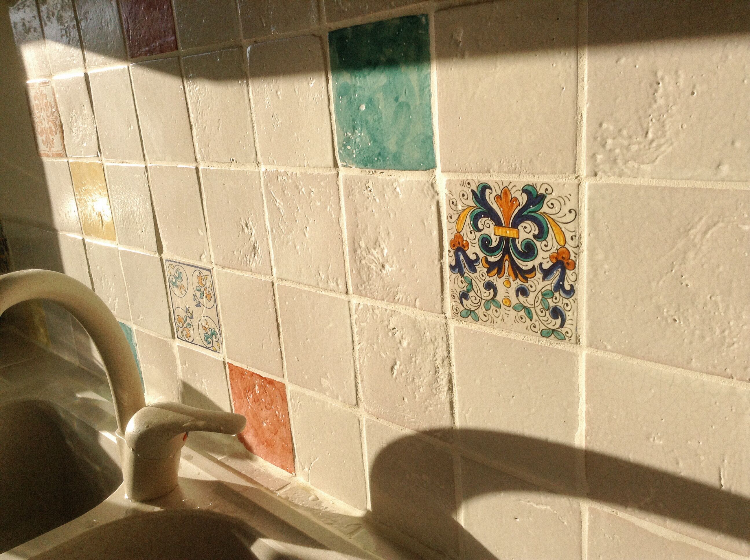A bathroom with a tiled wall featuring a variety of colors and patterns.