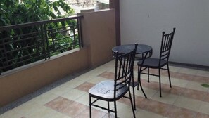 Enjoy dining or socializing on this balcony with a view of lush greenery.