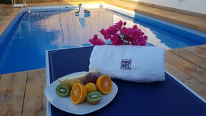 Ein Poolbereich mit Handtuch, Früchten und Blumen.