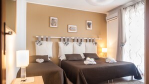 Ein Hotelzimmer mit zwei Betten, einem Nachttisch mit Lampe und einem Fenster mit Vorhängen.