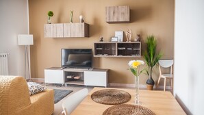 Ein modernes Wohnzimmer mit Fernseher, Sofa, Couchtisch und Dekorationselementen.