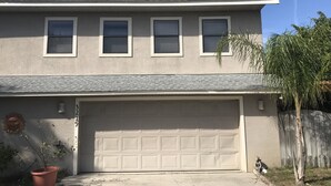 A two-story house with a garage, a small tree, and a decorative item on the wall.