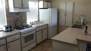 A kitchen with white cabinets, a stove, a refrigerator, and a sink.