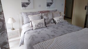 Ein Schlafzimmer mit einem Bett, Kissen, einem Nachttisch, einer Lampe und zwei an der Wand hängenden Hirschbildern.