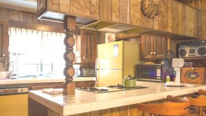 Una cocina con armarios de madera, un refrigerador amarillo, un microondas y una radio.