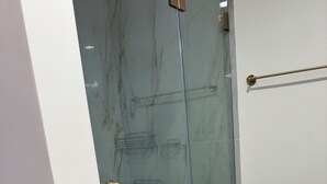 A glass-enclosed shower area with a metal handle and a towel rack on the wall.