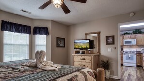 Een slaapkamer met een groot bed, een televisie en een houten dressoir.