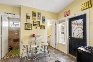Un corridoio con una porta, un piccolo tavolo con sedie e diversi elementi decorativi appesi al muro.