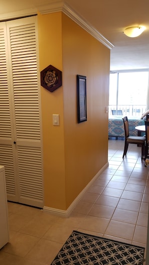 Um corredor com uma porta fechada, um quadro emoldurado e um tapete estampado.