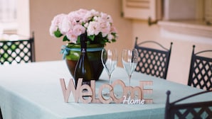 A table with a bottle of wine, two wine glasses, and a bouquet of flowers. - Ground floor villa apartment with garden and pool, 1 km from the city (Lucca)