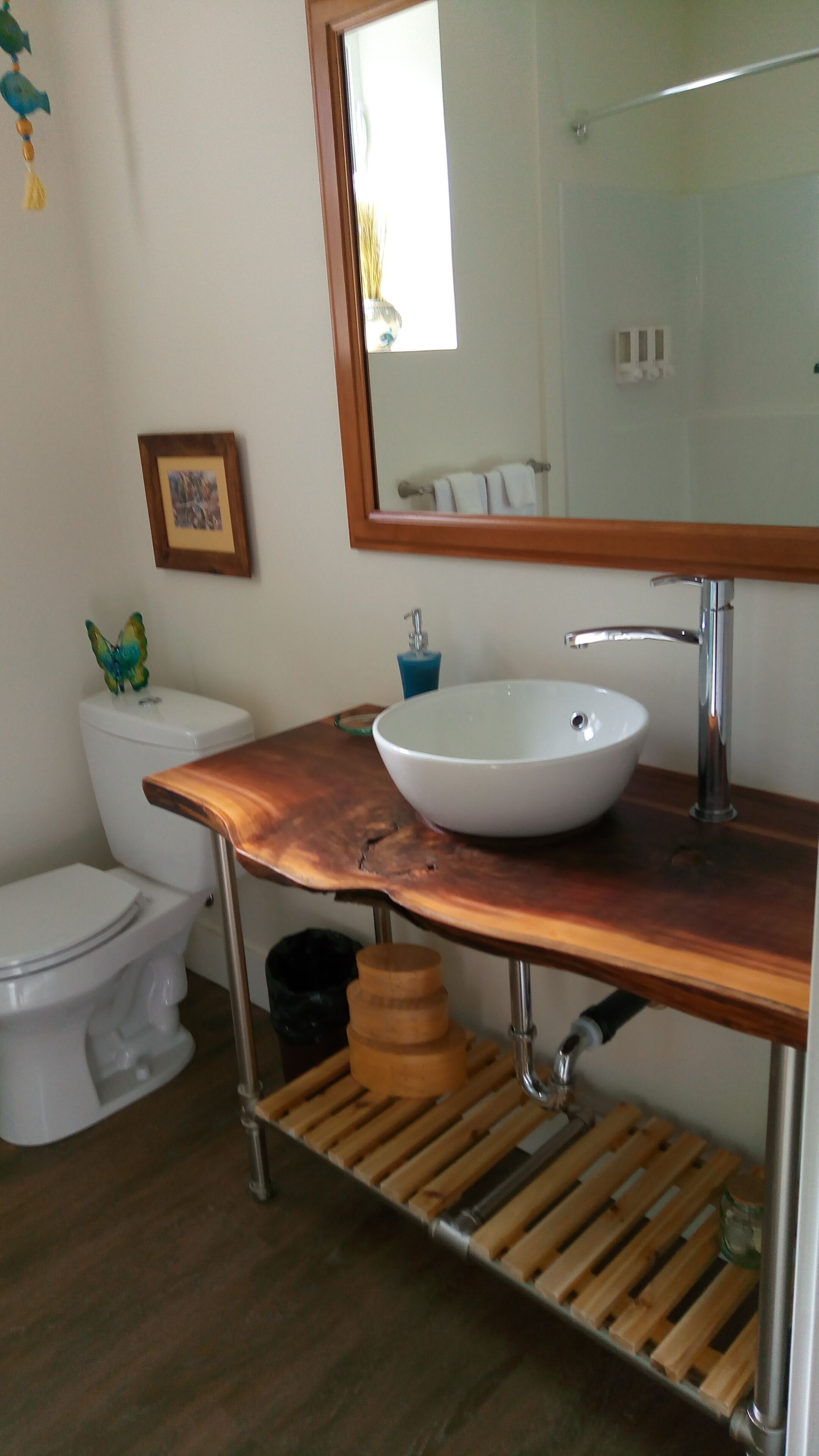 A bathroom with a white sink, a wooden vanity, a toilet, and a mirror.
