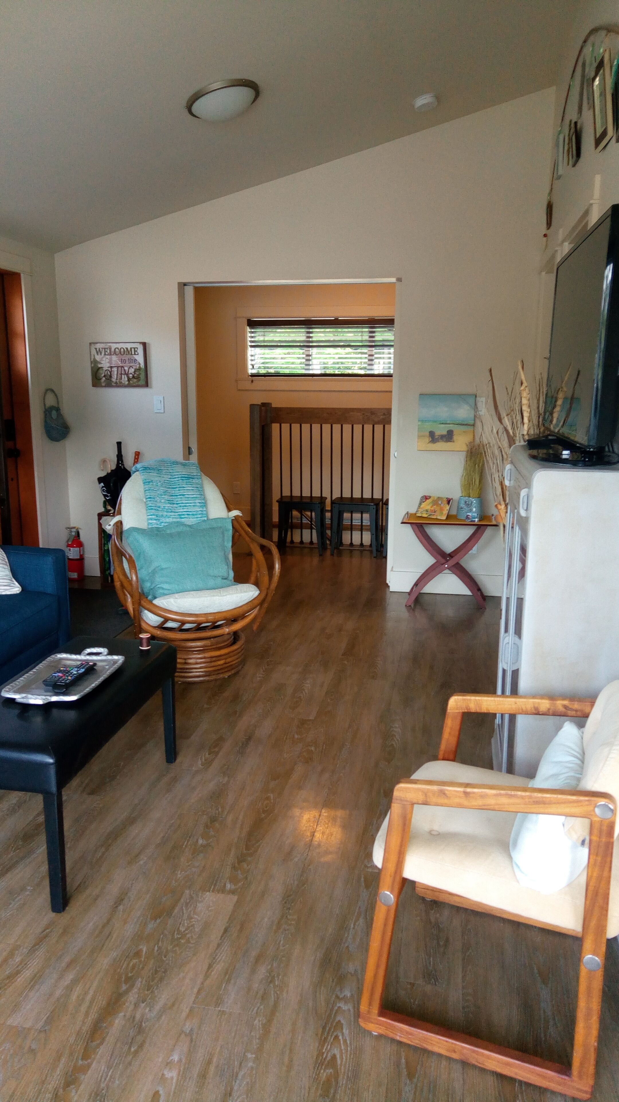 Un salon comprenant un canapé, un fauteuil en osier, une petite table et un téléviseur.