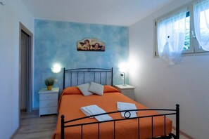 Cozy retreat with a bed, bedside tables, and a potted plant, set against a light blue backdrop.