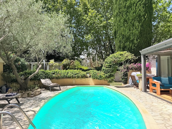 A swimming pool with a stone deck, surrounded by lush greenery and a pergola. - HOUSE OF 3 BEDROOMS 10 MIN WALK FROM THE CENTER OF SAINT REMY DE PROVENCE (Saint-Rémy-de-Provence)
