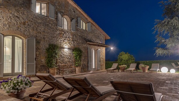 A stone building with a patio area featuring lounge chairs and potted plants. - VILLA SIENA is 4 km from Siena 10PAX AC, POOL & SPA total privacy. (Siena)