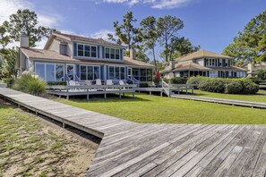 A two-story house with a covered deck and a small outdoor seating area.