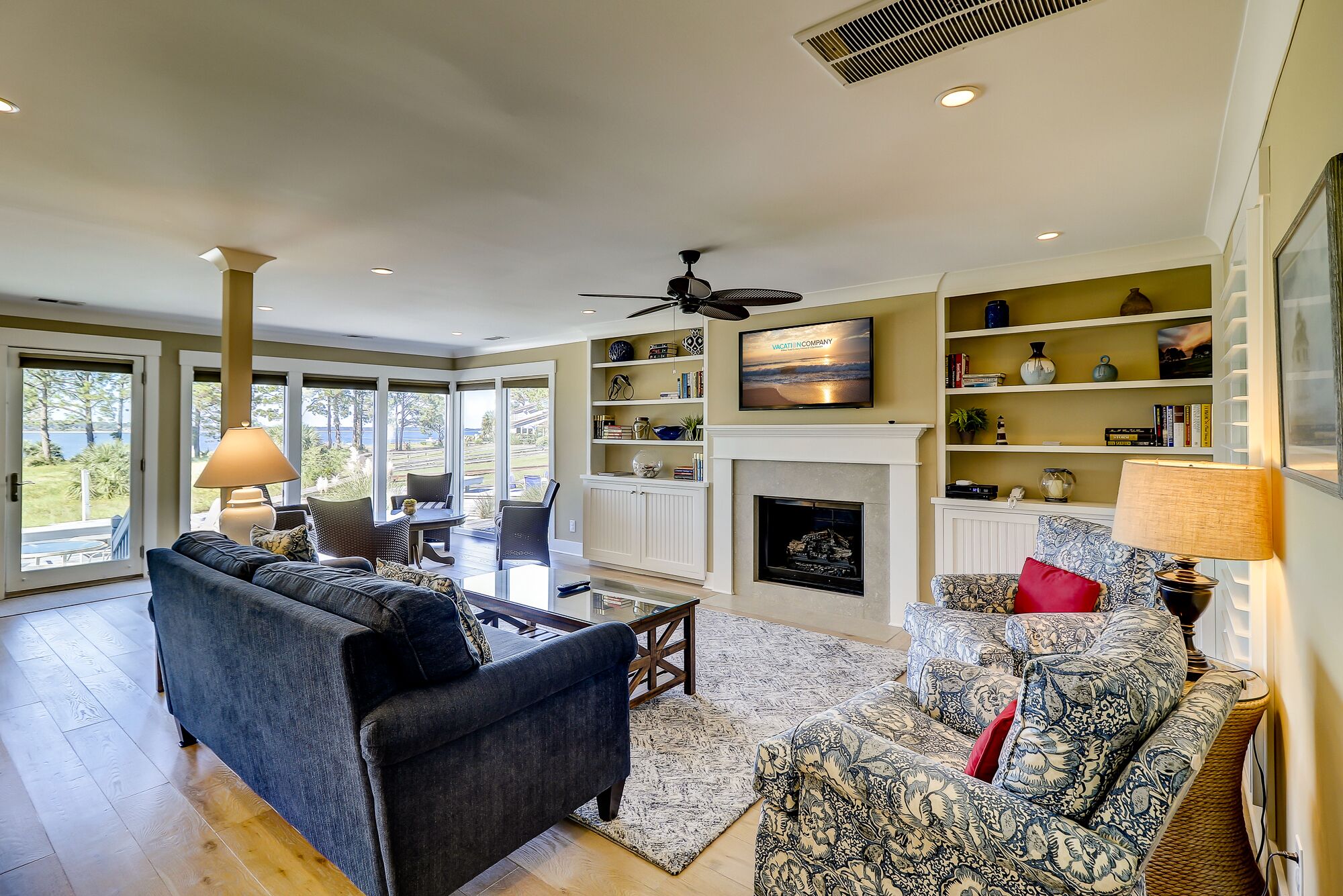 A spacious living room with a fireplace, large windows, and a television.