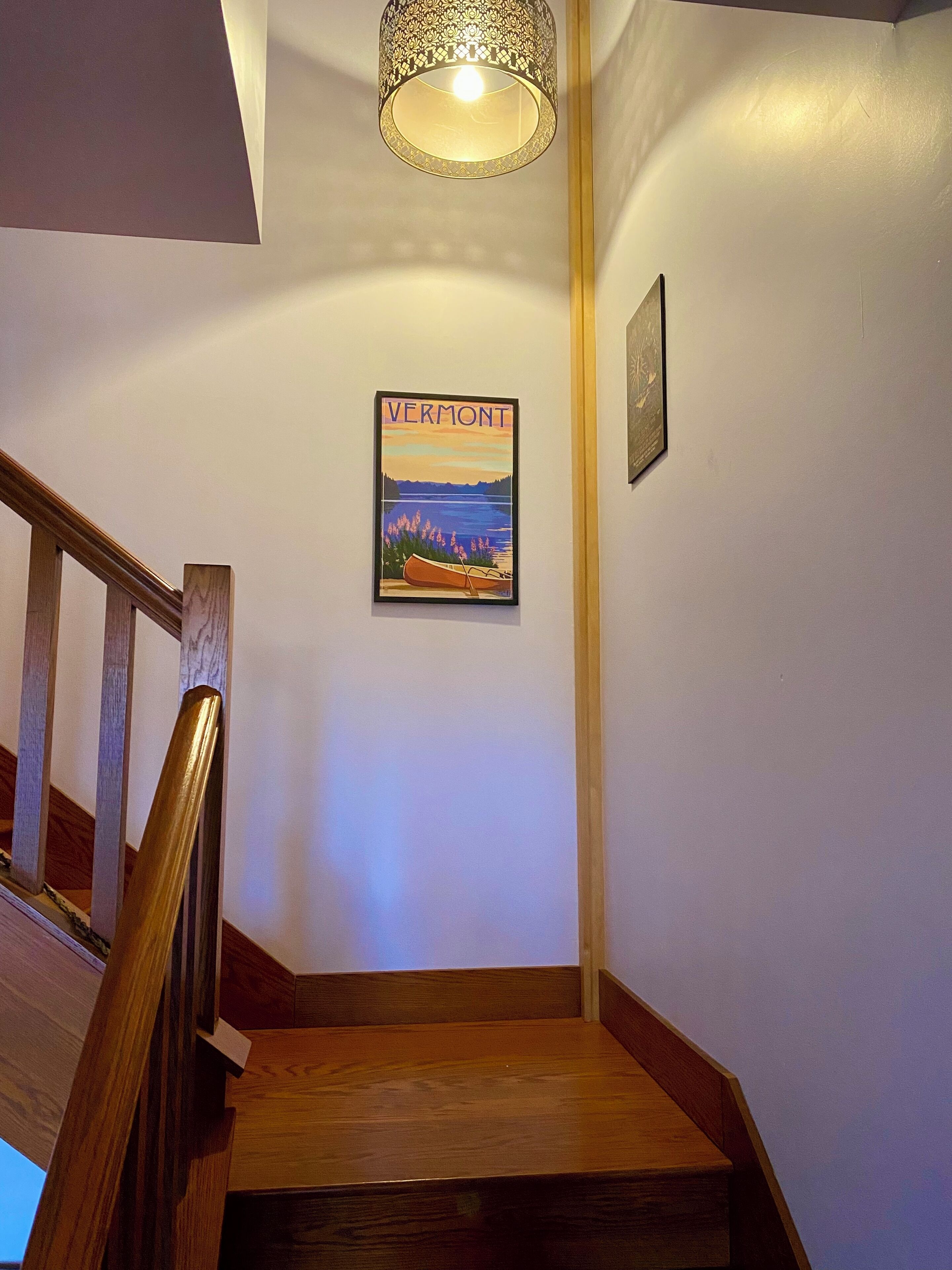 A wooden staircase with a framed Vermont poster on the wall.