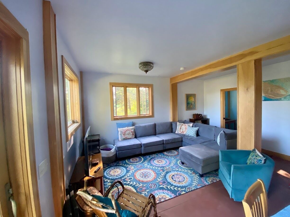 A living room with a grey sectional sofa, a blue armchair, and a patterned rug.
