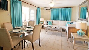 Una sala de estar con comedor, un sofá, una mesa de centro y un televisor.