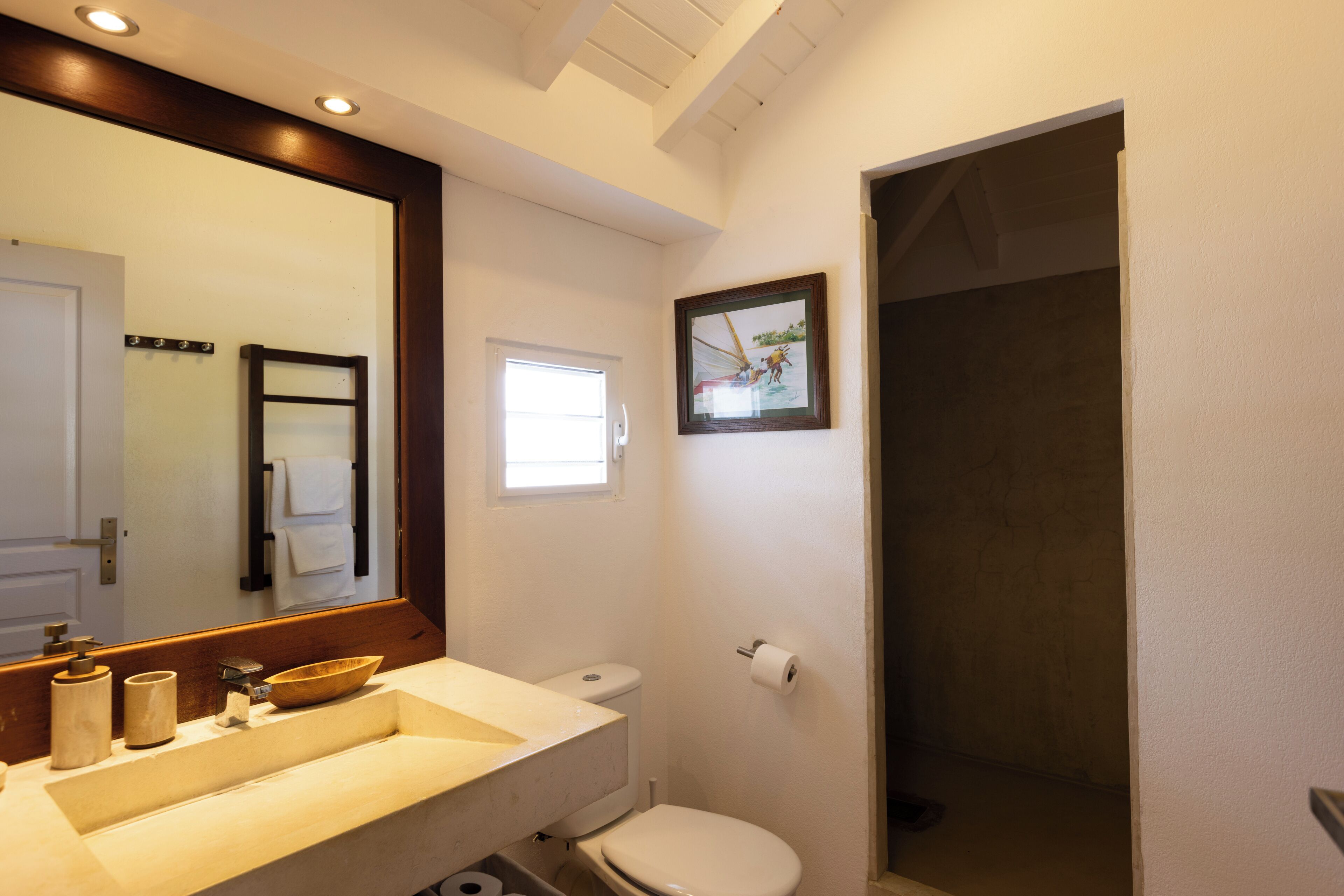 A bathroom with a sink, toilet, and a framed picture on the wall.