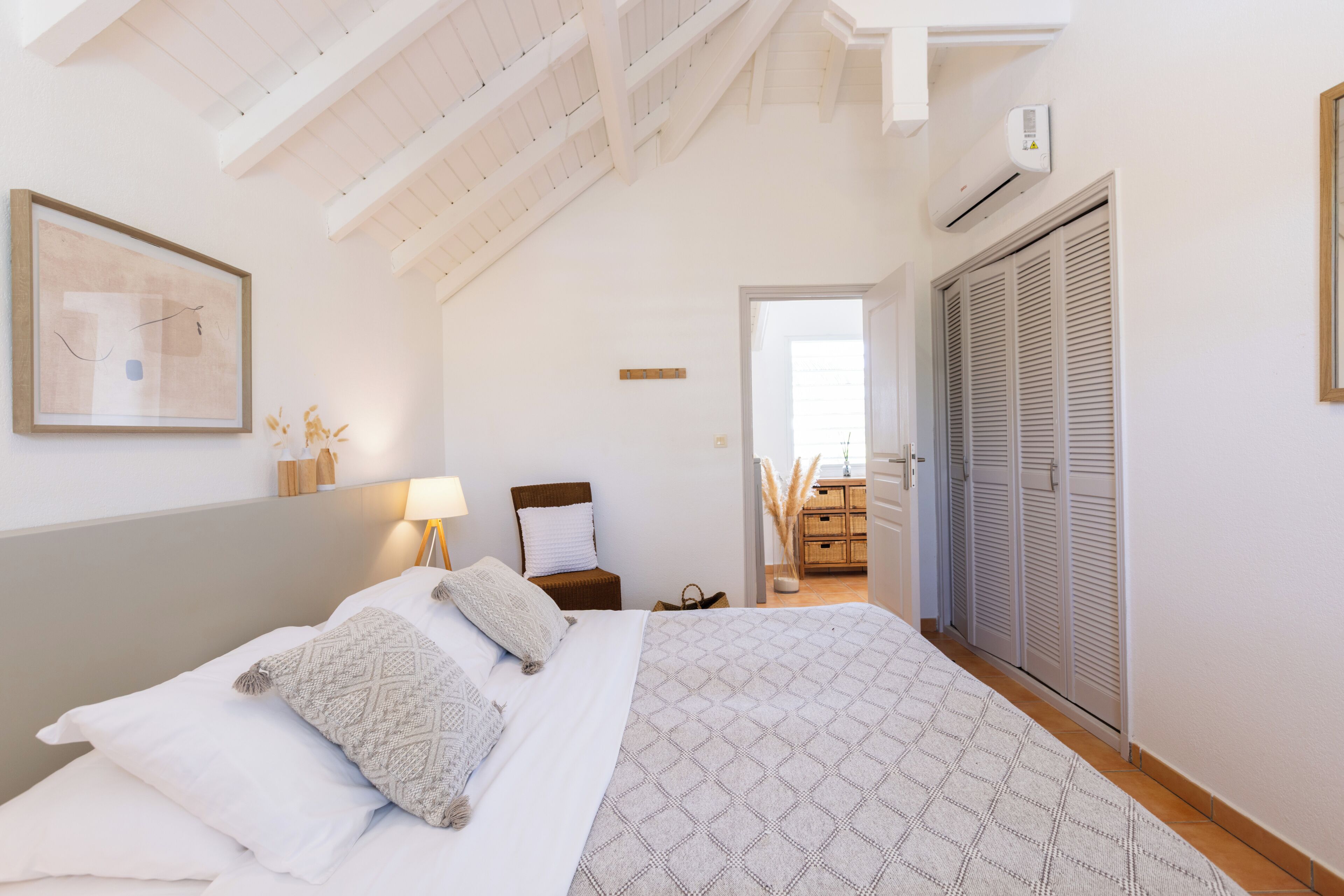 A bedroom with a bed, a nightstand, a lamp, a chair, and a wardrobe.