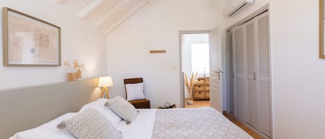 A bedroom with a bed, a nightstand, a lamp, a chair, and a wardrobe.