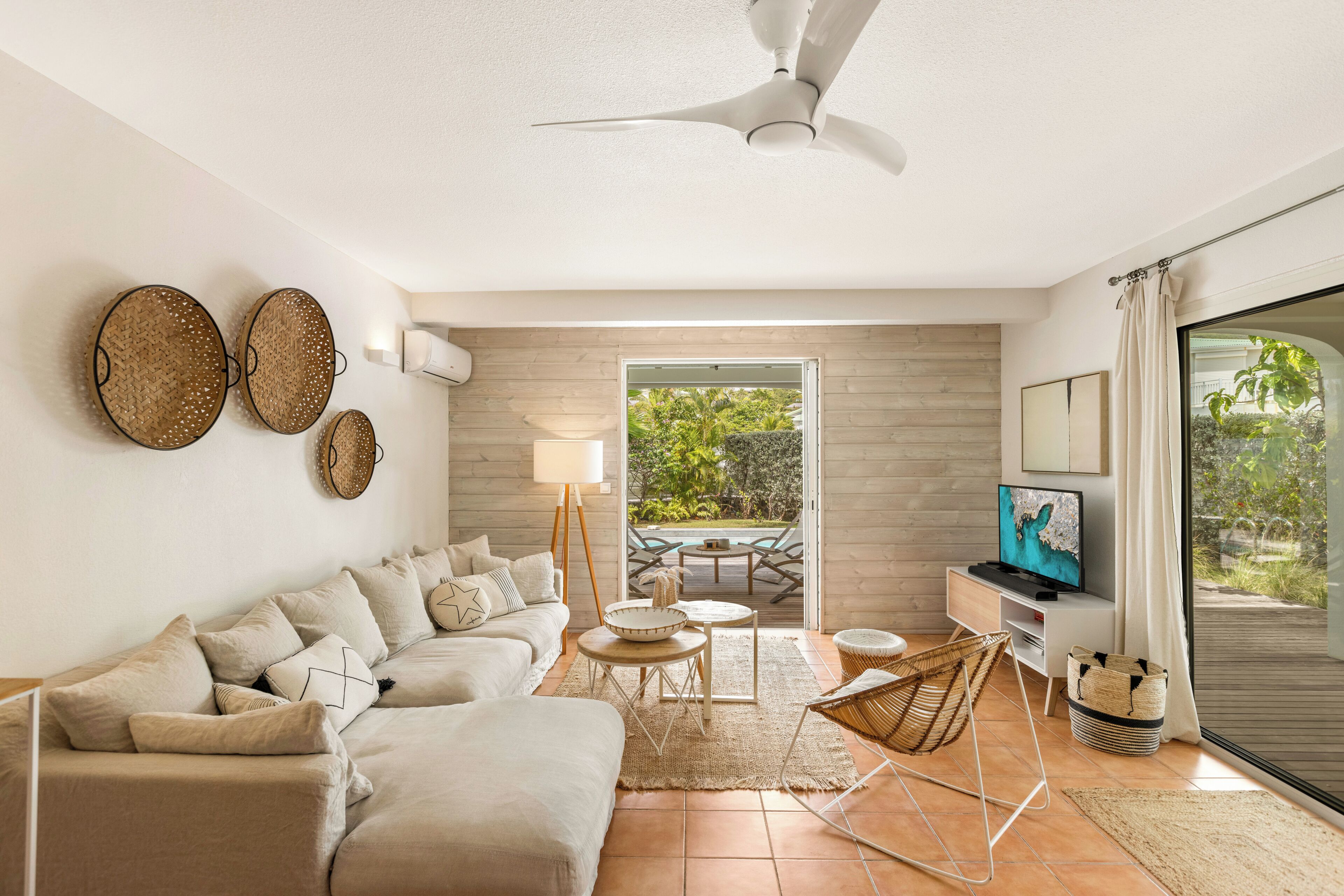 A modern living room with a sofa, television, and a view of the outdoors.