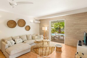 A modern living room with a sofa, round tables, and a TV.