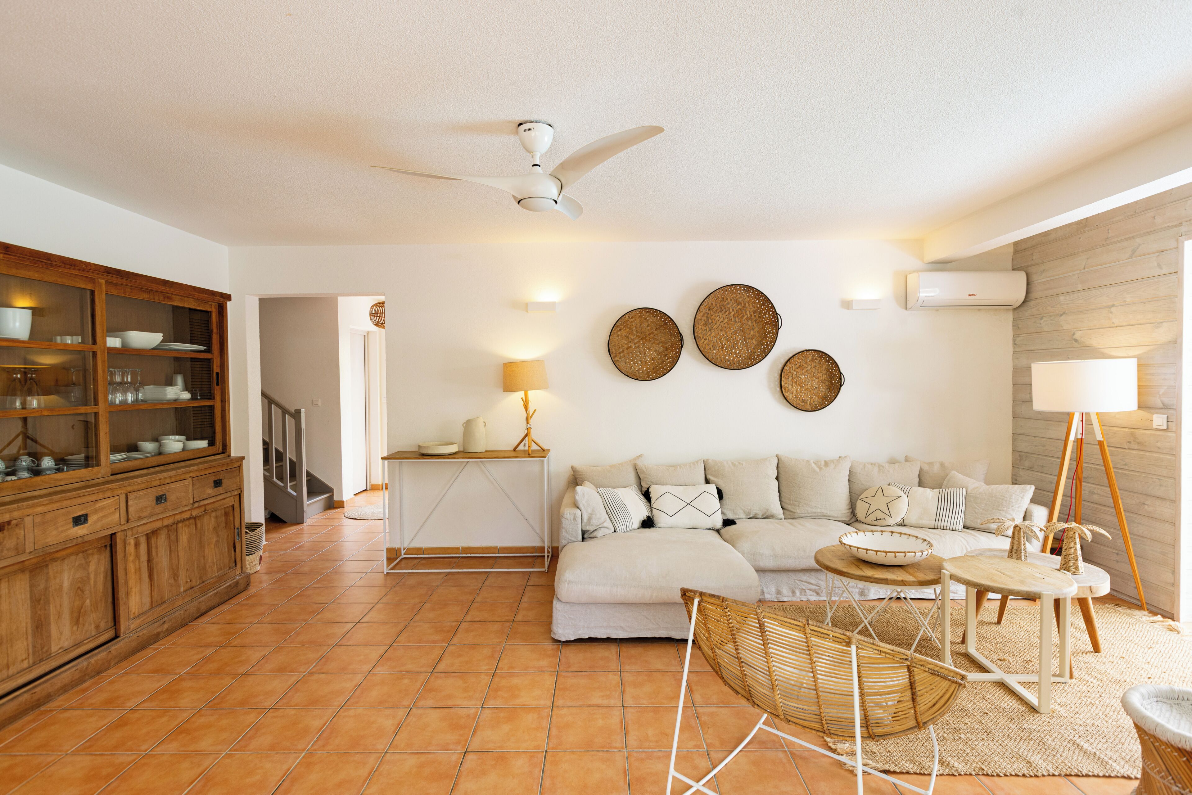Uma sala de estar com sofá, área de jantar com armário, ventilador de teto e decoração na parede.