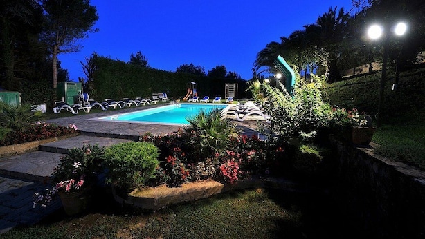 A nighttime swimming pool area with lounge chairs, a moon in the sky, and surrounding greenery. - Villino Alfredo A: A charming cottage situated in a quiet location, a few minutes from the town center, with Free WI-FI. (Massa Lubrense)