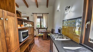 A kitchen with wooden cabinets, a stove, and a window with curtains. - Villino Alfredo A: A charming cottage situated in a quiet location, a few minutes from the town center, with Free WI-FI. (Massa Lubrense)