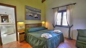 A bedroom with a bed, a nightstand, a mirror, a window with curtains, and a painting on the wall. - Villino Alfredo A: A charming cottage situated in a quiet location, a few minutes from the town center, with Free WI-FI. (Massa Lubrense)