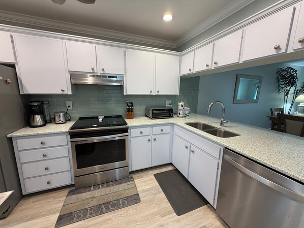A modern kitchen with white cabinets, stainless steel appliances, and a granite countertop.