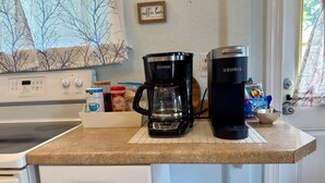 A kitchen counter with a coffee maker, a Keurig, and a box of creamer.