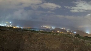 A coastal town at night with illuminated buildings and a winding road.