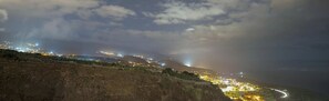 Un pueblo costero de noche con edificios iluminados y una carretera sinuosa.