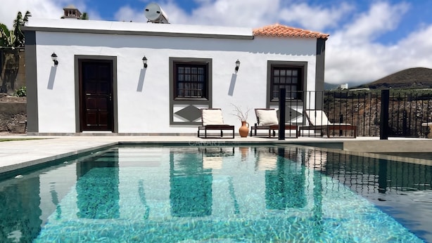 Un edificio moderno con piscina, zona de estar exterior y vistas a la montaña.