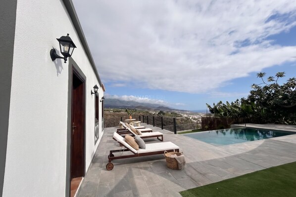 Un área junto a la piscina con sillones de descanso, una piscina y vistas al paisaje.