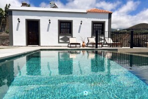 A modern building with a pool, outdoor seating, and a mountain view.