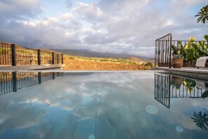 A swimming pool with a clear view of a hilly landscape in the background.