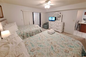 Ein Hotelzimmer mit zwei Betten, einem Fernseher, einem Schminktisch und einem Sessel.