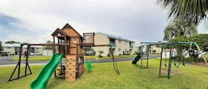 A playground with a slide, climbing wall, and swings.