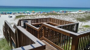 Eine Holzterrasse mit Blick auf einen Strand und das Meer.